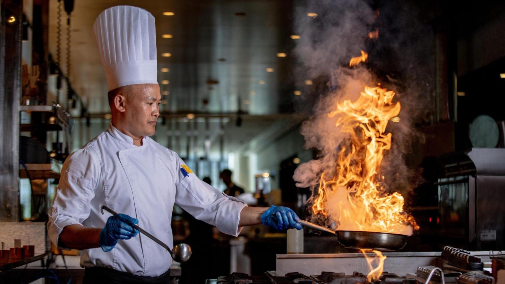 Voco Dubai By Ihg Hotel Luaran gambar A chef cooking with a flaming wok